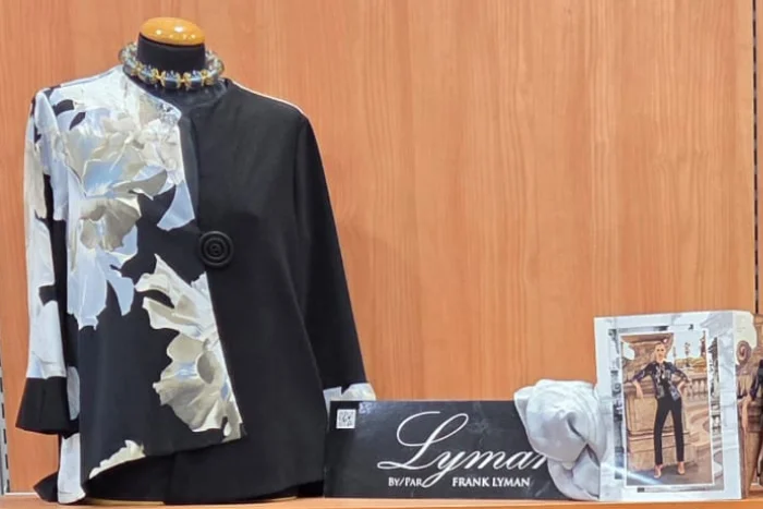 Giacca Frank Lyman nera con pannello asimmetrico a grandi fiori bianchi e grigi, chiusa da un bottone rotondo, su manichino